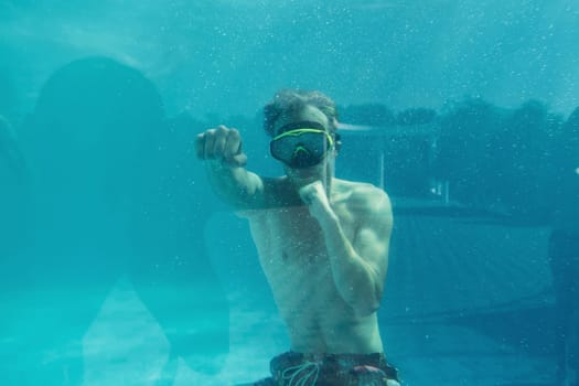 Man swimming underwater in the pool at daytime. Having fun.