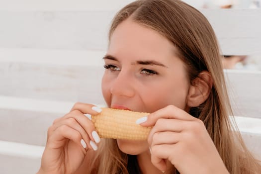 Healthy vegetarian hipster woman in summer outfit eat grilled corn and look to camera. Sexy lady on sea beach sunset or ocean sunrise. Travel, explore, active yoga and meditation lifestyle concept.