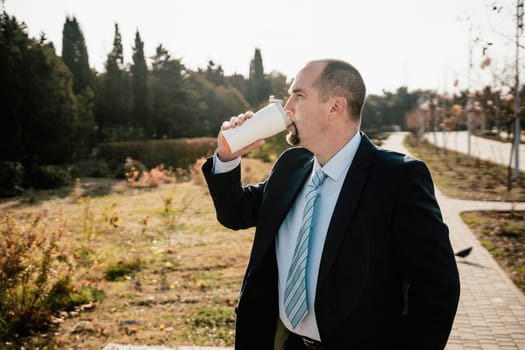 Mature entrepreneur drink coffee in autumn park. Senior executive rest in city park.