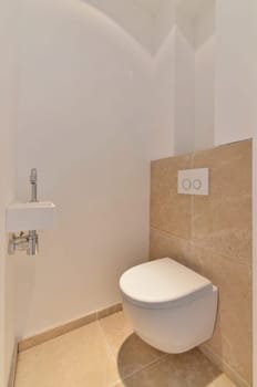 a toilet in the corner of a room with tile flooring and beige tiles on the walls, there is a white wall mounted