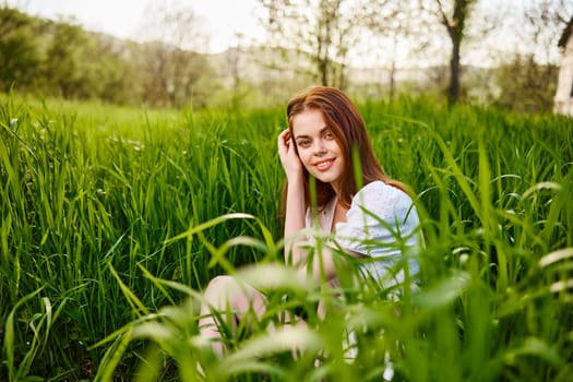 cute, contented woman sitting in tall green grass outdoors. High quality photo