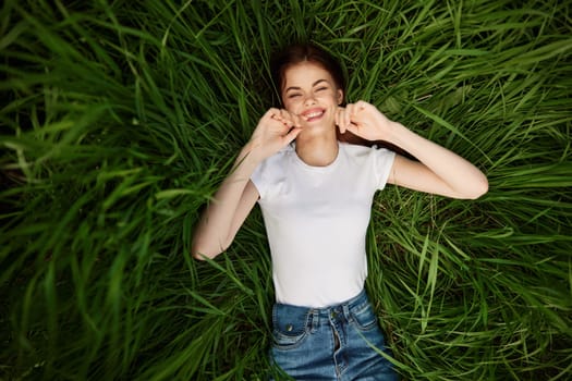 a woman with even, white teeth laughs in the green grass. High quality photo