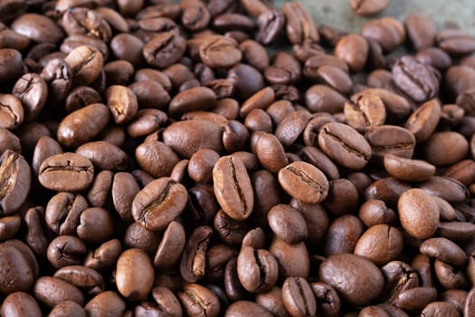 Close-up of roasted coffee beans on a green surface as a background. Selective focus.