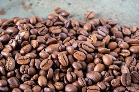 Close-up of roasted coffee beans on a green surface as a background. Selective focus.