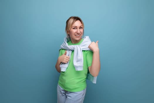 positive cheerful young woman in casual outfit on blue background with copy space.