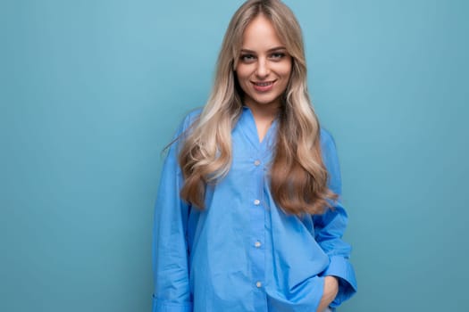 cheerful blond girl in a blue shirt isolated on a blue background.