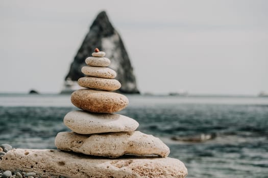 Pyramid stones on the seashore with warm sunset on the sea background. Happy holidays. Pebble beach, calm sea, travel destination. Concept of happy vacation on the sea, meditation, spa, calmness.