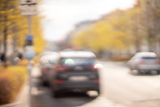 Autumn season bokeh background. Abstract city blur along the road with cars