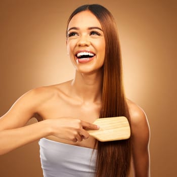 Hair brush, beauty and a happy woman in studio for growth and color shine or texture. Aesthetic female thinking, brushing and laugh for natural haircare, and hairdresser or salon on brown background.
