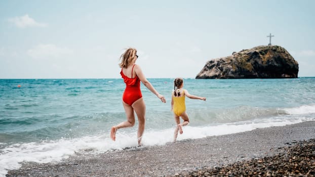 Happy loving family mother and daughter having fun together on the beach. Mum playing with her kid in holiday vacation next to the ocean - Family lifestyle and love concept.