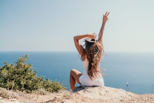 Woman travel sea. Young Happy woman in a long red dress posing on a beach near the sea on background of volcanic rocks, like in Iceland, sharing travel adventure journey