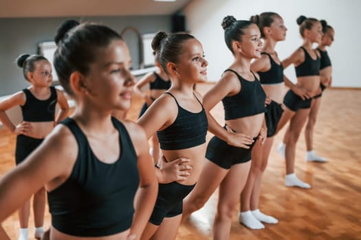 Group of female kids practicing athletic exercises together indoors.