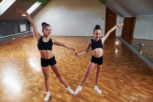 Training routine. Group of female kids practicing athletic exercises together indoors.