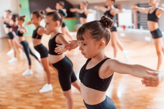 Active lifestyle. Group of female kids practicing athletic exercises together indoors.