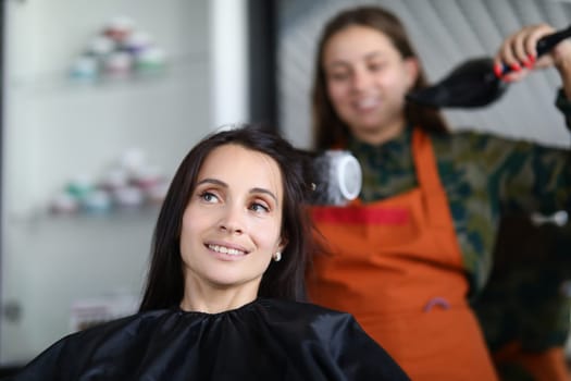 Hairdresser drying hair woman client in hairdressing beauty salon. Hair styling in beauty salon