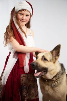 Portrait of Little girl in a stylized Tatar national costume with big shepherd dog on a white background in the studio. Photo shoot of funny young teenager who is not a professional model