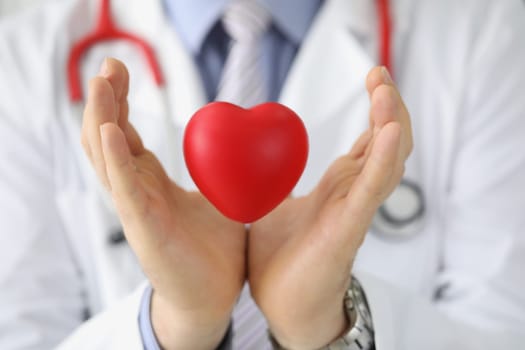 Doctor cardiologist holds red heart in air. Heart transplantation and cardiovascular disease