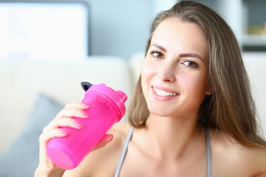 Portrait of sporty smiling beautiful woman with bottle of water. Sports and fat intake during exercise