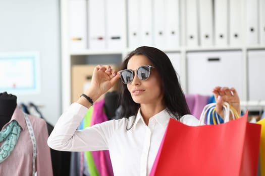 Stylish woman in sunglasses holding shopping bags. Discounts promotions and shopping for pleasure