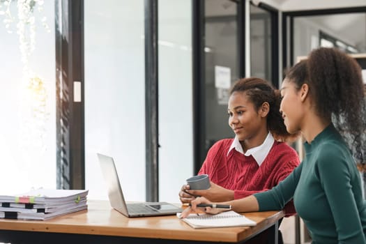 Young group of diverse students studying together using laptop at home. College multiracial people working on university group assignment homework project in modern apartment.