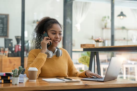 Beautiful American women student studying online takes notes on her laptop to gather information about her work smiling face and a happy study posture..