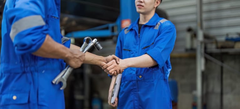 Two car mechanic team shaking hand at automobile service center. Repair service concept. Car repair and maintenance. Car mechanic working at automotive team service center..