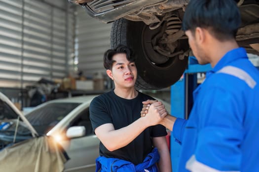 Two car mechanic team shaking hand at automobile service center. Repair service concept. Car repair and maintenance. Car mechanic working at automotive team service center..