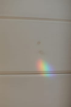 Abstract natural light rainbow on white wall mock up. light refraction on white wall, blurred sun rays refracting through glass prism with shadow.
