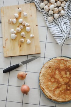 cutting raw mushrooms at table in kitchen. Homemade pancakes. Breakfast or dinner, cooking at home