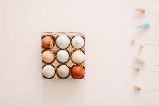 fresh chicken eggs of natural shades and colors in a recycled box on a white background.