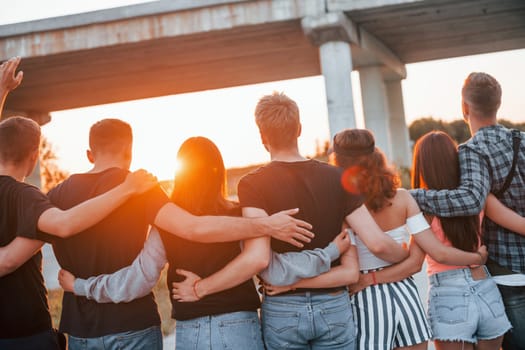 View from behind. Group of young cheerful friends having fun together. Party outdoors.