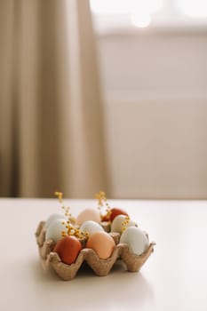fresh chicken eggs of natural shades and colors in a recycled box on a white background.