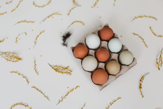 fresh chicken eggs of natural shades and colors in a recycled box on a white background.