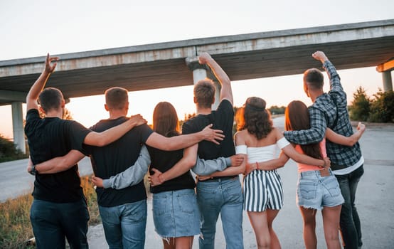 View from behind. Group of young cheerful friends having fun together. Party outdoors.