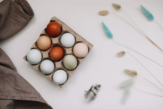 fresh chicken eggs of natural shades and colors in a recycled box on a white background.