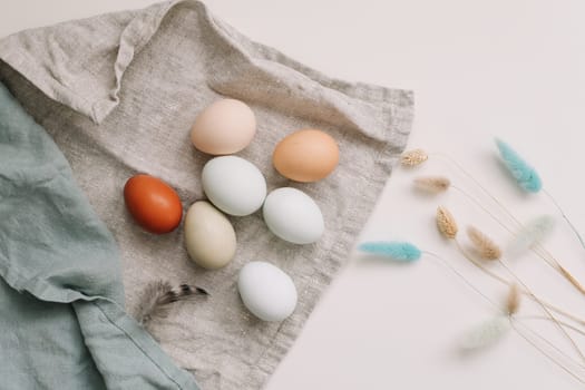 fresh chicken eggs of natural shades and colors in a recycled box on a white background.