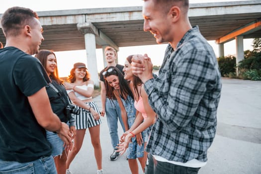 Talking and laughing. Group of young cheerful friends having fun together. Party outdoors.