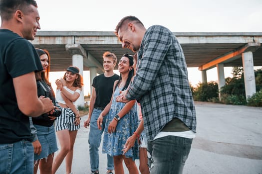 Talking and laughing. Group of young cheerful friends having fun together. Party outdoors.