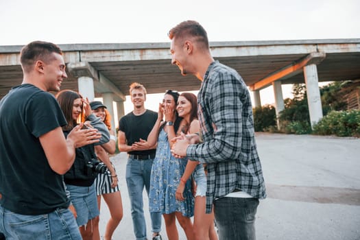 Talking and laughing. Group of young cheerful friends having fun together. Party outdoors.