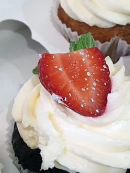 A small cake with a slice of fresh strawberries close-up on the table.