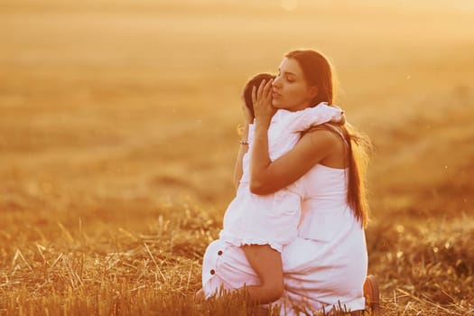 Positive little girl with her mother have weekend outdoors on the summer field together.