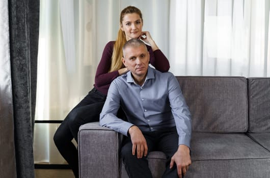 A married couple is sitting on a sofa in an apartment.