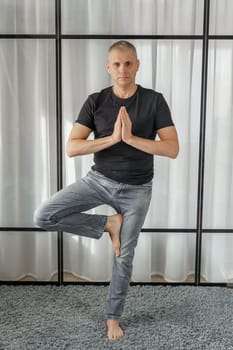 A man practicing yoga in the office on a break, exercise - Tree Pose.