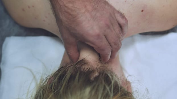 Men's hands massage the neck for a young girl