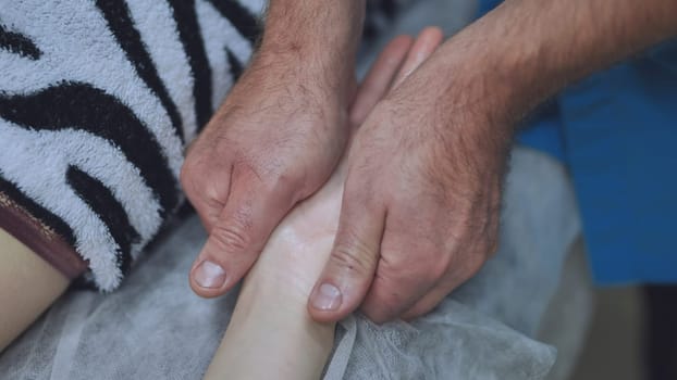 A masseur massages the wrists of a girl