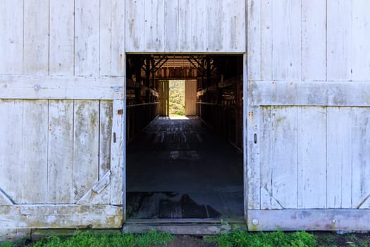 Open barn door with dark interior and bright exterior on historic Pierce Point Ranch in Point Reyes, California. High quality photo