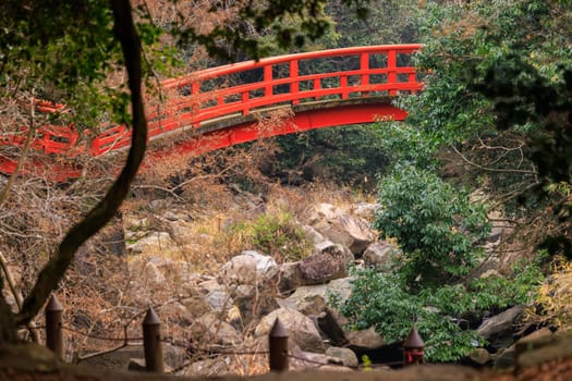 Arched red bridge over dry rocky river in quiet forest. High quality photo