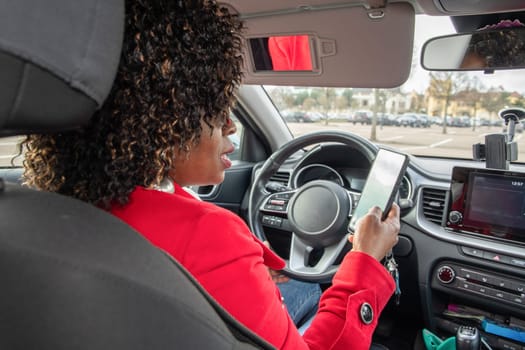 Satisfied young african american woman video chatting in car with someone on mobile phone in parked car, using technology, High quality photo