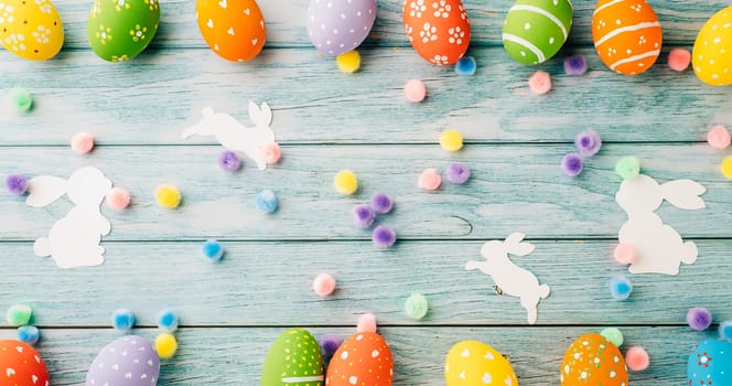 Easter Day Concept. Top view holiday banner background web design white colorful easter eggs and paper bunny rabbit on blue wood background with copy space, celebration greeting, overhead, template