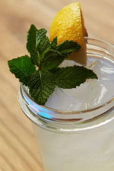 With lemon and mint. Close up view of fresh summer alcoholic cocktail on the wooden table.